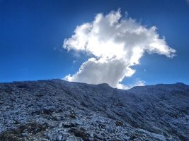 Hinter dem Vorgipfel steigen Wolken auf.