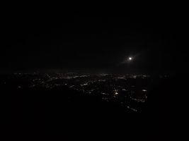 Der Mond über dem nächtlich beleuchteten Tiefland