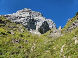 Unter der schattigen Felswand durch die breite Grasrinne weiter hoch.